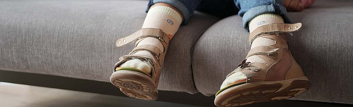 Kinderfüße mit Orthesen-Schuhen