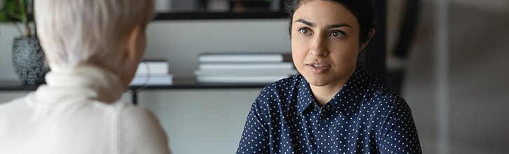 Zwei Frauen im Gespräch, eine Frau ist nur von hinten zu sehen