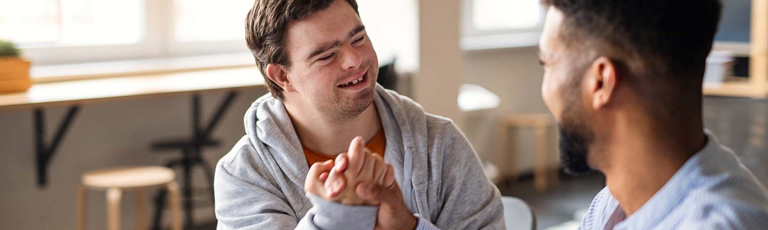 Zwei Männer machen einen Bro-Handschlag, einer hat Down Syndrom